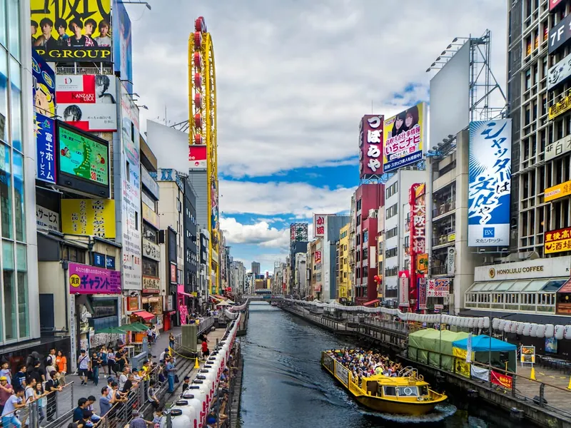 River cruise boat on the Dotonbori canal in Osaka, lined with neon signs